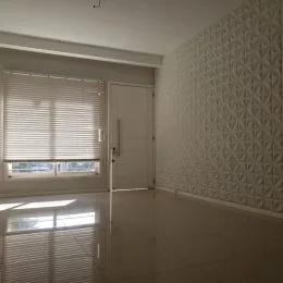 Foto de um cômodo interno com piso reflexivo e janela coberta por persianas.