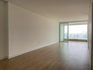 Ambiente interno de uma sala ampla com piso de madeira e vista panorâmica da cidade.