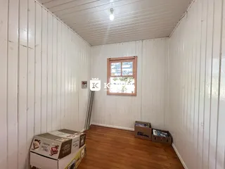 Foto de um cômodo interno com paredes brancas e piso de madeira.