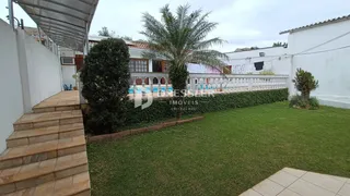 Vista externa de um jardim com piscina e muro branco em Lajeado.