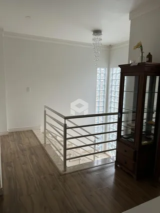 Hall com piso de madeira e corrimão de metal na área interna.