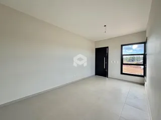 Interior de uma sala ampla com piso de cerâmica e janela.