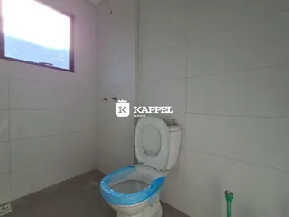 Foto de um banheiro com paredes brancas e um vaso sanitário visível.