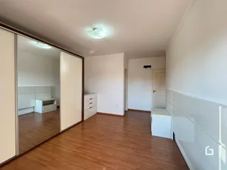 Hall de entrada com piso de madeira e portas brancas.