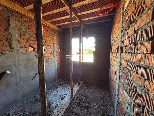 Interior de um cômodo com paredes de tijolo aparente e vigas de madeira expostas.