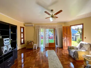 Sala de estar com piso de madeira e porta de vidro abrindo para o exterior.