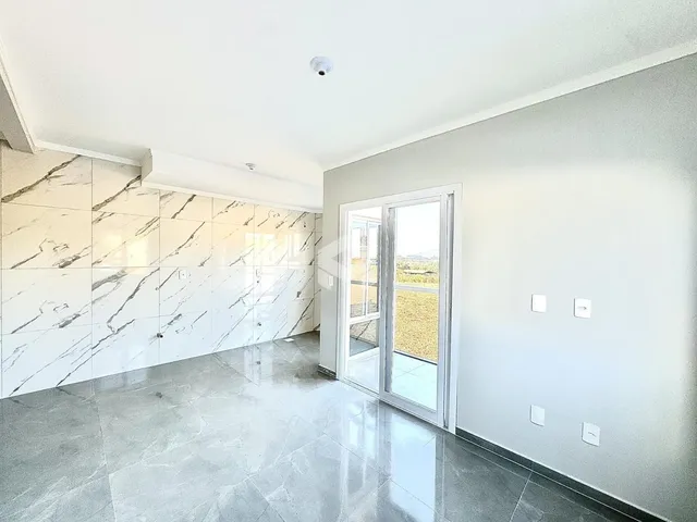 Interior de uma sala com revestimento de mármore branco e piso claro.