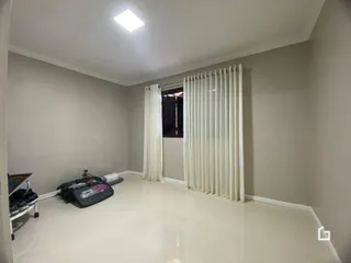 Ambiente interno de uma sala ampla com paredes claras e piso branco.
