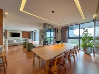 Uma sala de jantar ampla com piso de madeira e grandes janelas.