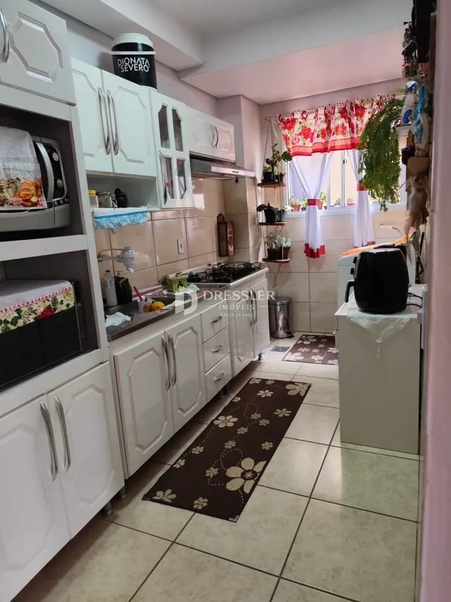 Foto de uma cozinha com armários brancos e piso de cerâmica.