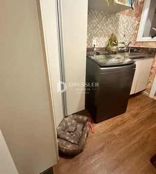 Área da cozinha com armários brancos e piso de madeira visíveis.