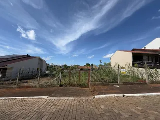 Vista externa de uma propriedade residencial com cerca e vegetação no primeiro plano.