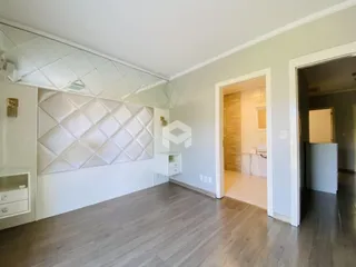 Sala de estar com piso de madeira clara e parede decorativa.