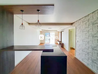 Ambiente interno com piso de madeira e iluminação pendente em um espaço aberto.