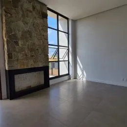 Ambiente interno com parede de pedra e grande janela.