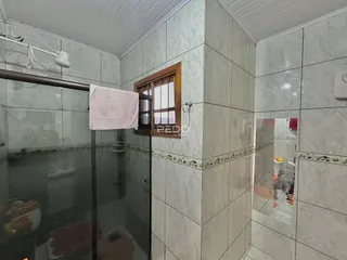 Um banheiro com paredes de azulejo claro e box de vidro.