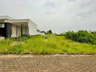 Vista da fachada de uma residência em Lajeado, Brasil, com vegetação alta no primeiro plano.