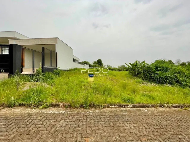 Vista da fachada de uma residência em Lajeado, Brasil, com vegetação alta no primeiro plano.