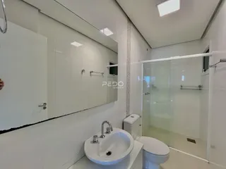 Banheiro moderno com revestimento branco e box de vidro.