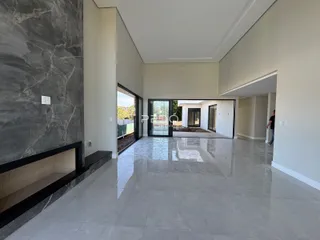 Ambiente interno de uma sala de estar com piso de grande formato e parede de mármore escuro.