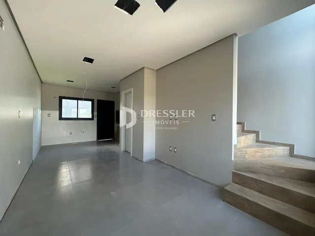 Interior de um espaço amplo com paredes brancas e piso claro.