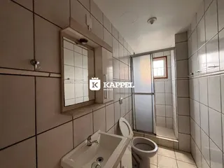 Banheiro com revestimento de azulejos brancos e pia de apoio.