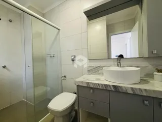 Banheiro com box de vidro e bancada de mármore claro.