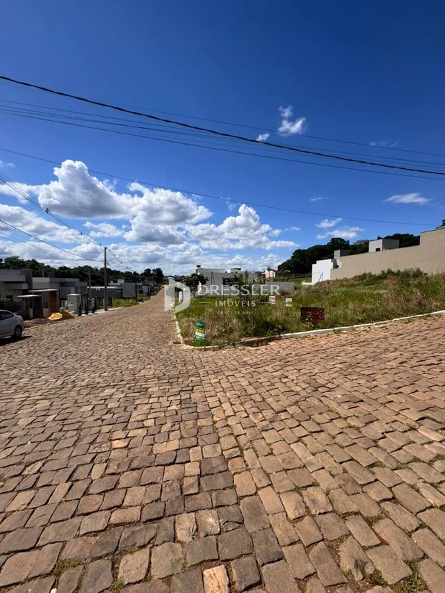 Vista da fachada de uma rua pavimentada com pedras no exterior de uma propriedade.