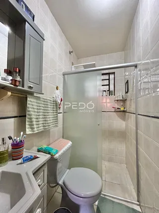 Foto de um banheiro com azulejos brancos e box de vidro.
