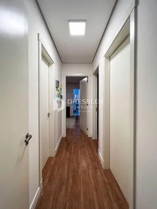 Corredor interno de uma residência com piso de madeira.