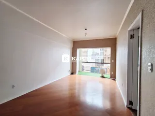 Sala de estar ampla com piso de madeira clara e acesso a uma área externa.