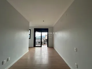 Corredor interno com piso de madeira e porta de vidro que dá para a vista externa.