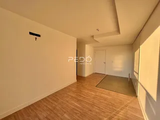 Interior de um ambiente com piso de madeira clara e paredes brancas.