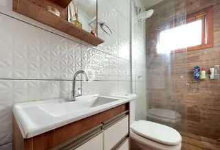 Banheiro com revestimento de azulejos brancos e bancada de madeira.