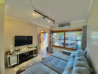 Sala de estar com sofá e televisão montada na parede.