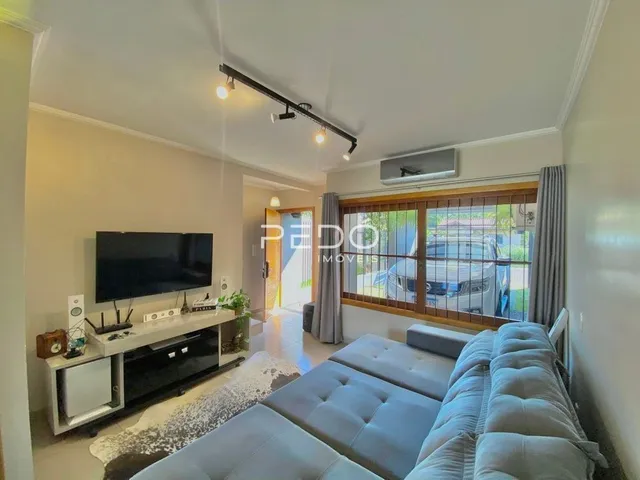 Sala de estar com sofá e televisão montada na parede.