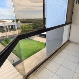 Vista de um jardim verde através de uma janela de uma varanda.