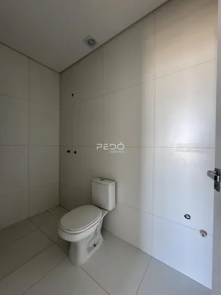 A foto mostra o interior de um banheiro com revestimento branco.