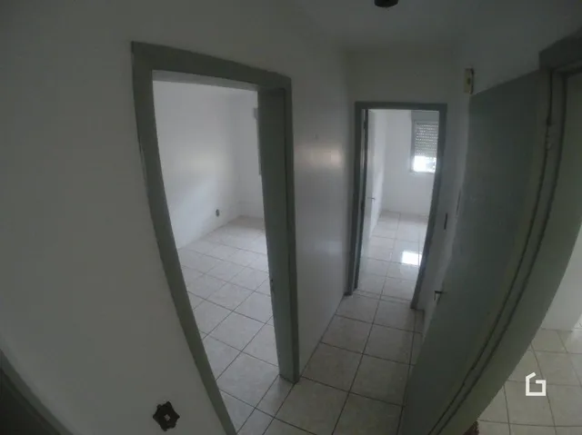 Corredor interno de uma residência com piso de cerâmica clara.