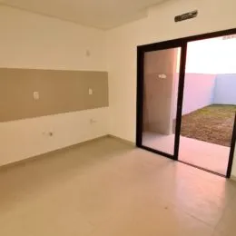 Ambiente interno de uma sala ampla com paredes brancas e piso claro.