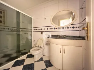 Banheiro com piso xadrez azul e branco e box de vidro.