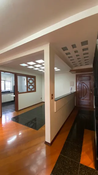Vista de um interior com piso de madeira e paredes brancas.