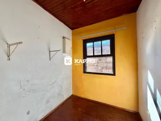 Foto de um cômodo interno com paredes brancas e piso de madeira.