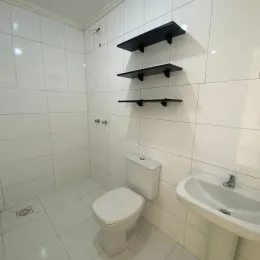 Foto interna de um banheiro com revestimento de azulejos brancos.