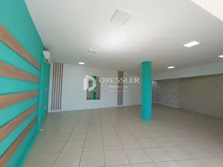 Interior de uma sala ampla com paredes azul-claro e piso de cerâmica.