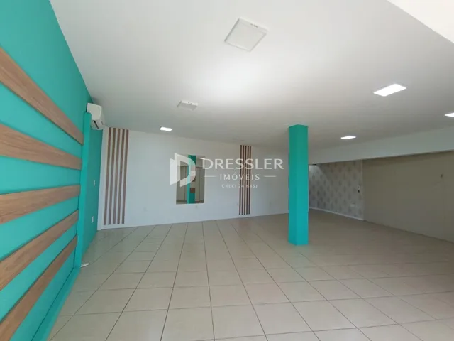 Interior de uma sala ampla com paredes azul-claro e piso de cerâmica.