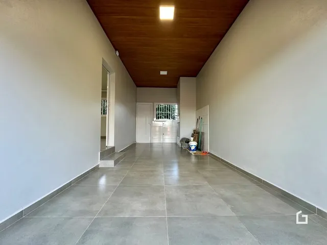 Corredor interno de uma residência com piso de cerâmica e teto de madeira.