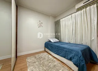 Quarto com cama e cortinas brancas em um imóvel.