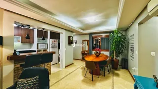 Ambiente interno de sala de jantar com mesa redonda de madeira.