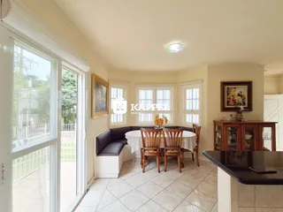 Sala de jantar com mesa e bancos em um ambiente claro com vista para o exterior.